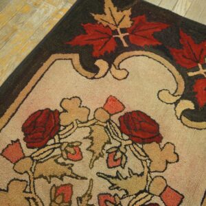 Coarse textured rug featuring red roses and autumn leaves on a beige field over distressed wooden floorboards.