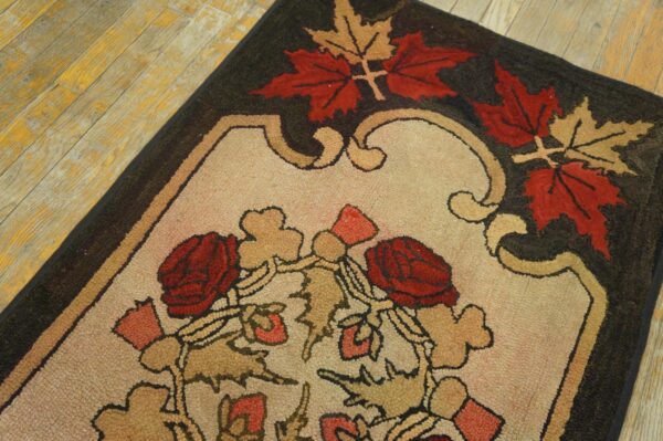 Coarse textured rug featuring red roses and autumn leaves on a beige field over distressed wooden floorboards.