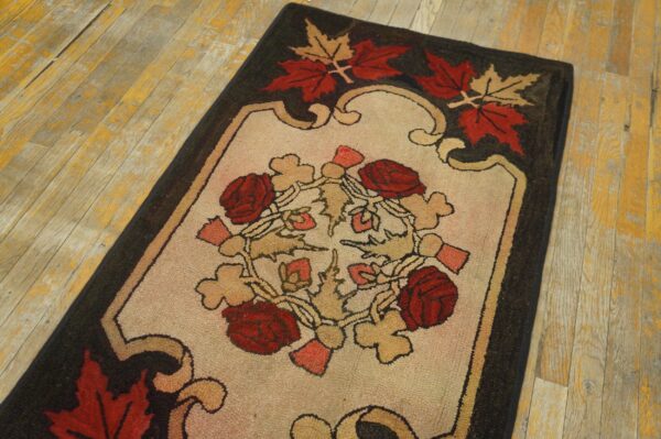 This dark floral rug, featuring red roses and maple leaves, is displayed on distressed yellow hardwood floors.