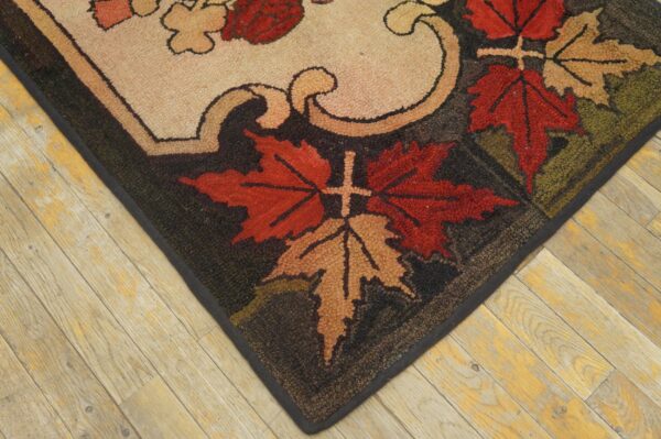 Chunky-pile rug corner with autumn leaf patterns in red and tan rests on rustic wood flooring.
