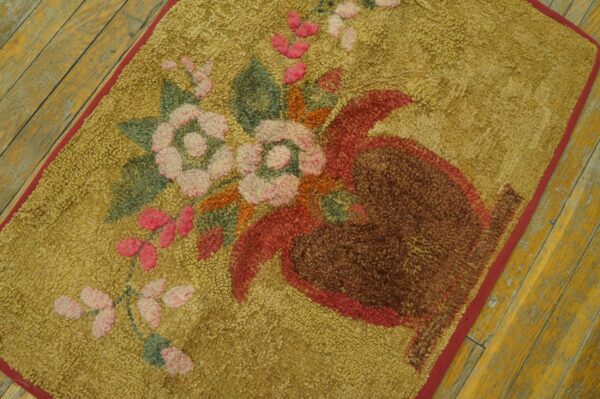 Golden looped rug with pink florals and a brown vase resting on rustic yellow wood planks.