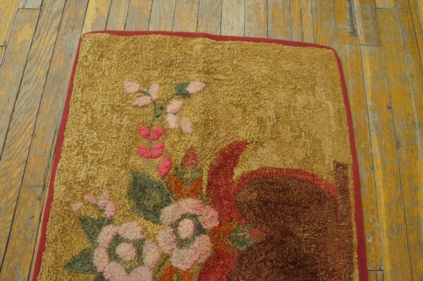 Looped gold rug featuring a dense floral pattern in pink, green, and red on distressed yellow wood floors.