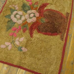 Textured mustard rug with pink and brown floral motifs, bordered in red, on distressed wood flooring.