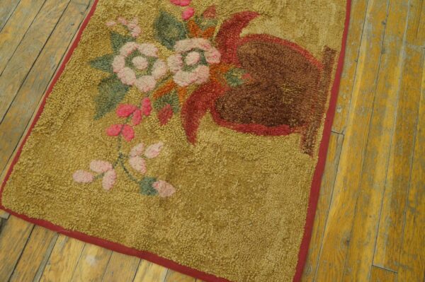 Textured mustard rug with pink and brown floral motifs, bordered in red, on distressed wood flooring.