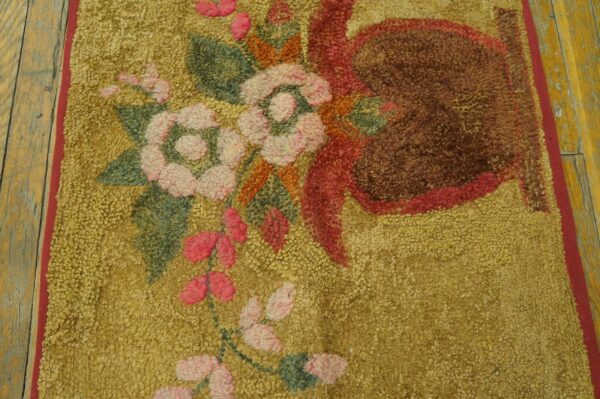 Highly textured gold rug with floral elements in pink, green, and deep brown, visible on wood planks.