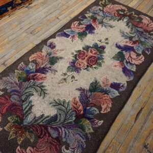 Textured rectangular rug with a central rose motif and colorful leaves on a dark brown background.