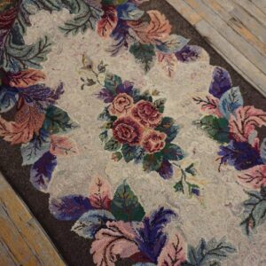 Textured rug runner features a multicolored rose and leaf design on rustic wooden floorboards.