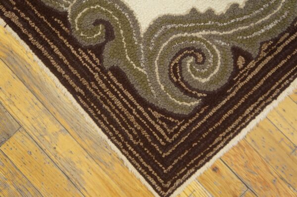 Textured brown, olive, and cream rug corner featuring a bold scroll pattern on light hardwood planks.
