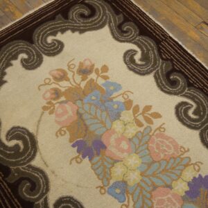 Detailed view of a cream rug featuring pastel florals and an olive green scrolled border on rustic wood planks.