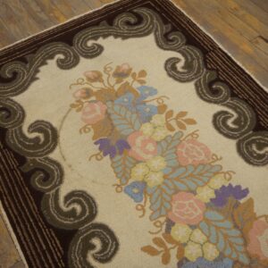 Textured cream rug with a pink and blue floral centerpiece and a bold dark border on wood.