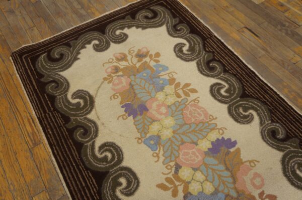 Textured cream rug with a pink and blue floral centerpiece and a bold dark border on wood.
