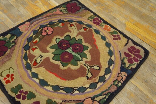 Textured rug featuring a central burgundy floral design and multi-colored concentric borders on wood planks.