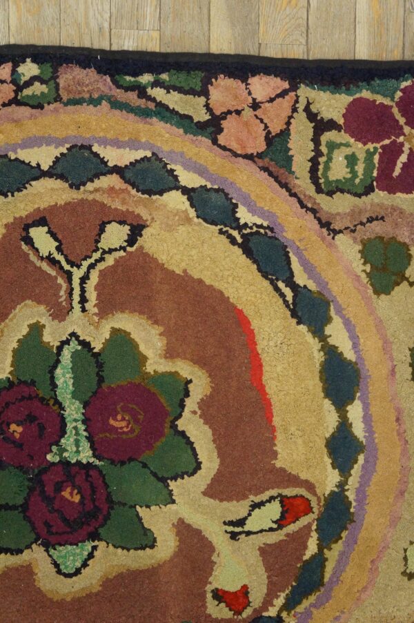 Textured loop rug featuring a bold floral design in rust, gold, burgundy, green, and purple on plank flooring.