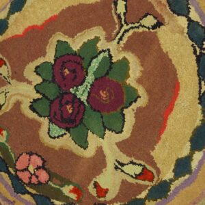 Close-up of a high-pile rug showing a floral pattern and colorful scalloped bands of brown, gold, and teal.