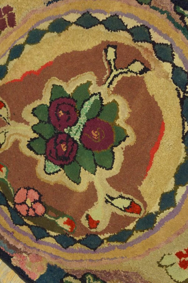 Close-up of a high-pile rug showing a floral pattern and colorful scalloped bands of brown, gold, and teal.