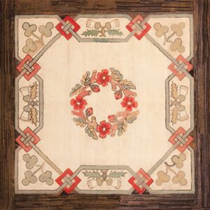 Square rug with a cream center, red floral wreath, framed by gray and red knots, surrounded by a dark brown border.
