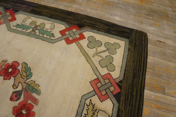 A richly textured rug corner displays red flowers, geometric shapes, and a dark striped border on wood floorboards.