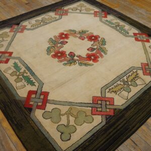 Beige diamond rug featuring a red floral wreath, green foliage, and a dark striated border on wooden flooring.