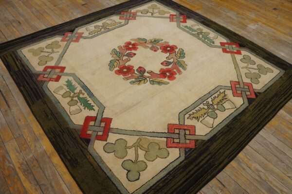Beige diamond rug featuring a red floral wreath, green foliage, and a dark striated border on wooden flooring.