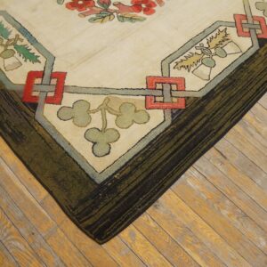 Textured rug corner featuring cream, red, and green stylized floral and geometric motifs on wooden planks.