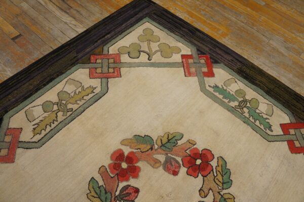 A textured cream rug with floral and geometric patterns in red, green, and brown lies on distressed wood flooring.