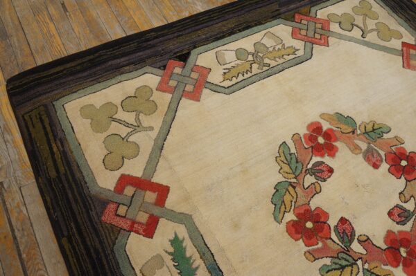 A textured cream rug with red and green floral and geometric patterns lies on worn wooden flooring.