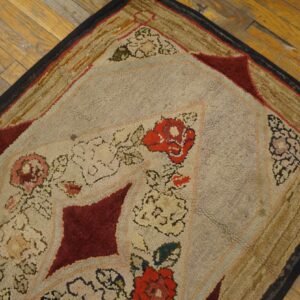 Beige, red, and gold chunky looped rug with floral and geometric patterns rests on wood planks.