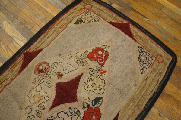 Beige, red, and gold chunky looped rug with floral and geometric patterns rests on wood planks.