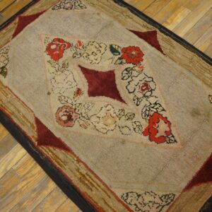 Heavily textured rug with red floral patterns and a light beige field rests on warm wood plank flooring.