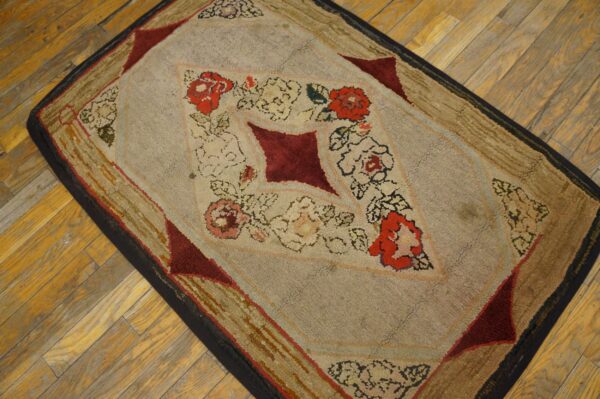 Heavily textured rug with red floral patterns and a light beige field rests on warm wood plank flooring.