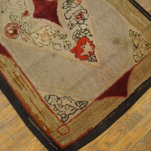 Textured beige and red floral rug corner with golden borders rests on rustic diagonal wooden flooring.