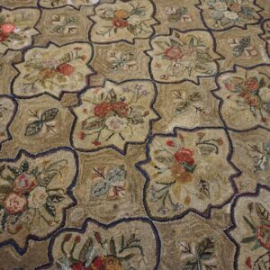 A textured, low-pile rug with beige quatrefoil medallions featuring multicolored floral bouquets.