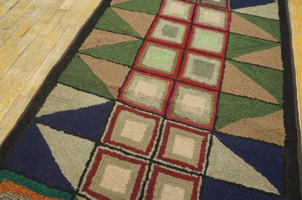 Geometric textured runner rug featuring concentric squares and triangles on yellow wood planks.