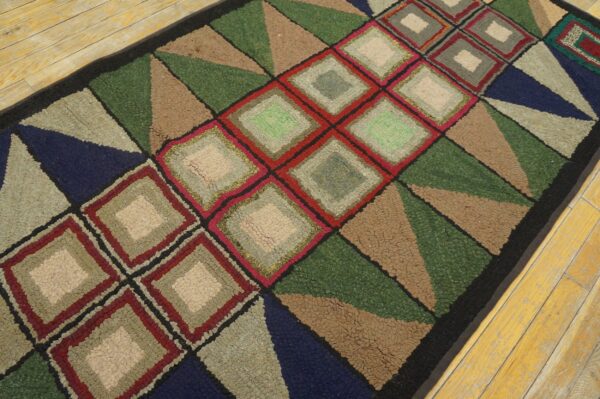 Multicolor hooked rug runner featuring bold green, red, navy, and tan geometric diamonds and triangles on wood flooring.