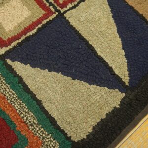 Textured hooked rug with geometric blocks of navy, maroon, green, and tan on a yellow plank floor.