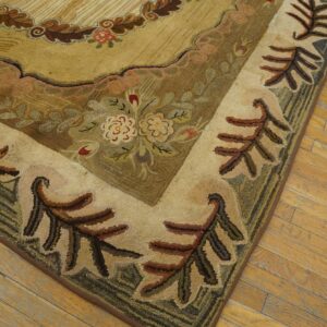 High-pile rug corner with tan, brown, and green floral motifs rests on worn hardwood floor.