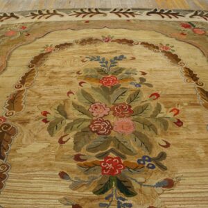 Textured golden rug with a large, colorful floral bouquet framed by a decorative leaf border on wood flooring.