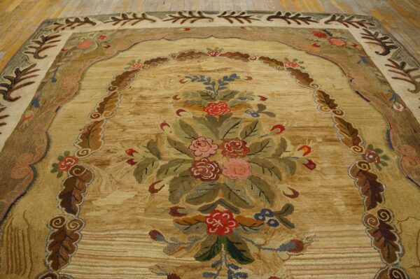 Textured golden rug with a large, colorful floral bouquet framed by a decorative leaf border on wood flooring.