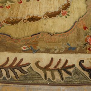 Highly textured gold rug featuring dense floral and scrolling patterns in red, brown, and green on wood flooring.