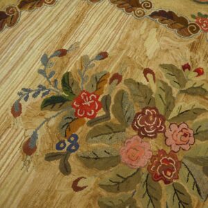 Textured low-pile rug close-up showing a dense floral bouquet of red, pink, and green on a striped beige ground.