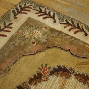 Earth-toned rug corner with complex floral motifs and large leaf borders sits on worn plank wood flooring.