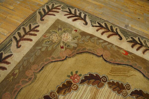 Earth-toned rug corner with complex floral motifs and large leaf borders sits on worn plank wood flooring.
