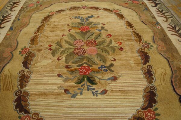 Detailed view of a textured beige rug with an arched, colorful floral bouquet and carved leaf borders.