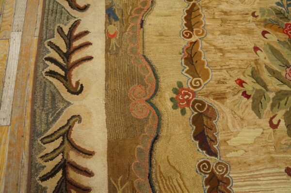 Textured, multi-colored hooked rug with bold floral borders lies next to distressed plank wood flooring.