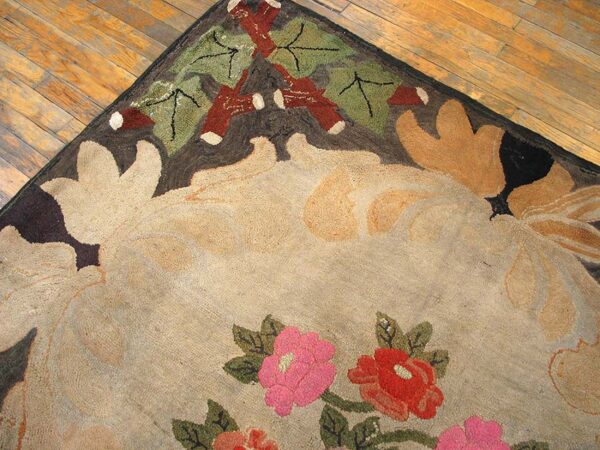 Beige rug with large floral pattern, pink and red blooms, and dark brown border on wood planks.