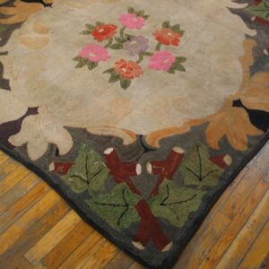 A thick floral rug with pink flowers and green leaves rests on worn wooden floor planks.