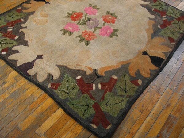 A thick floral rug with pink flowers and green leaves rests on worn wooden floor planks.