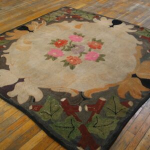 Square rug with a beige center, pink and red flowers, and a dark leaf border on plank hardwood.