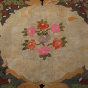 Floral rug with a beige center featuring red, pink, and purple blossoms, framed by dark and rust borders.