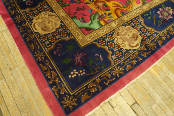 Multicolored rug corner with ornate pink, blue, and gold patterns rests on distressed wooden floorboards.